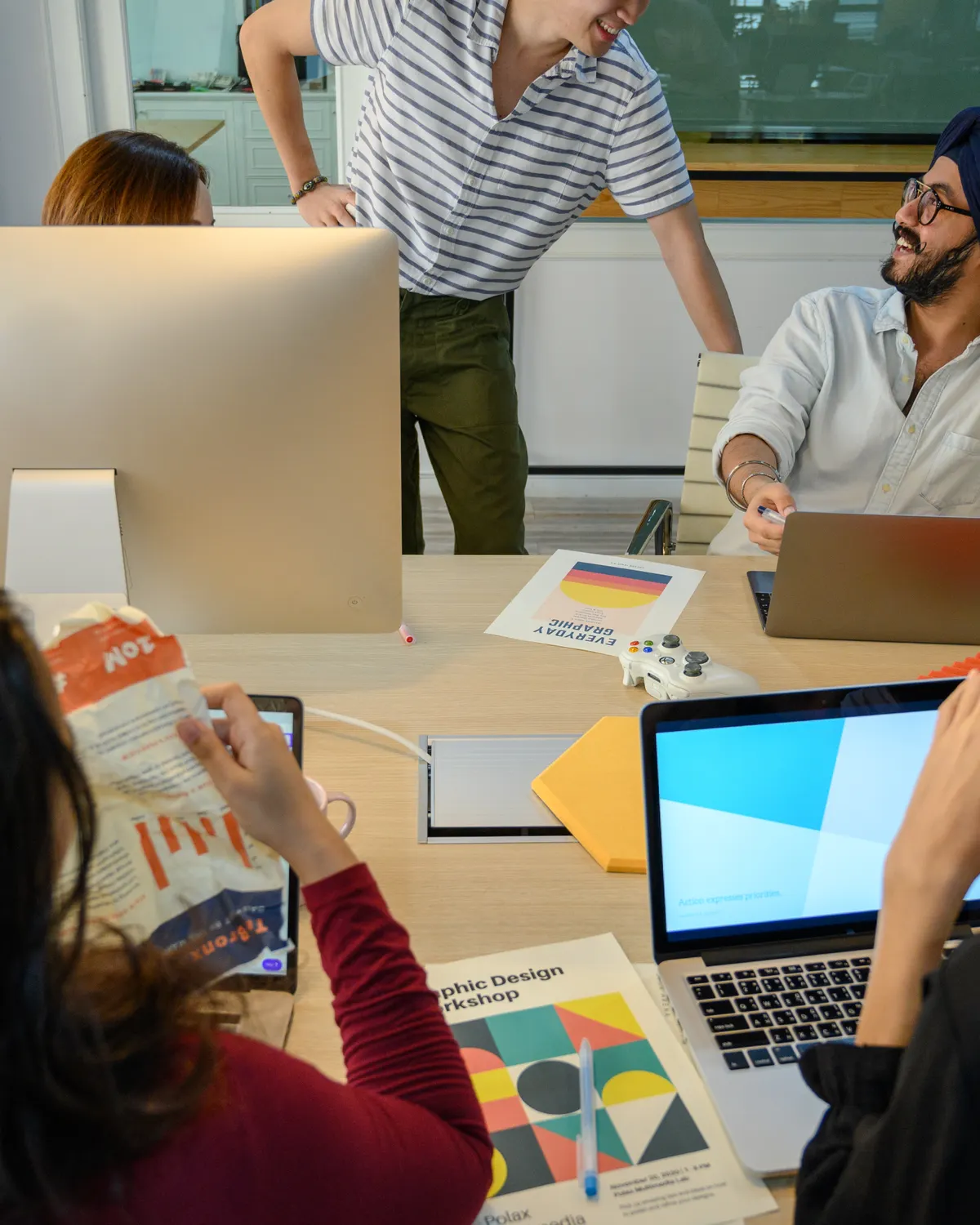 A diverse creative team collaborating around digital design work in an office