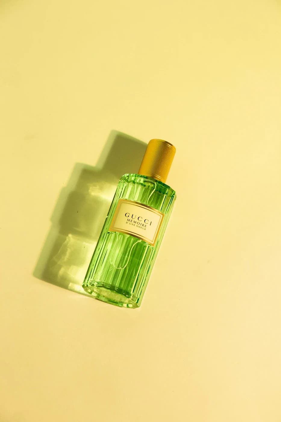 Green Gucci perfume bottle with directional light and a sculptural shadow