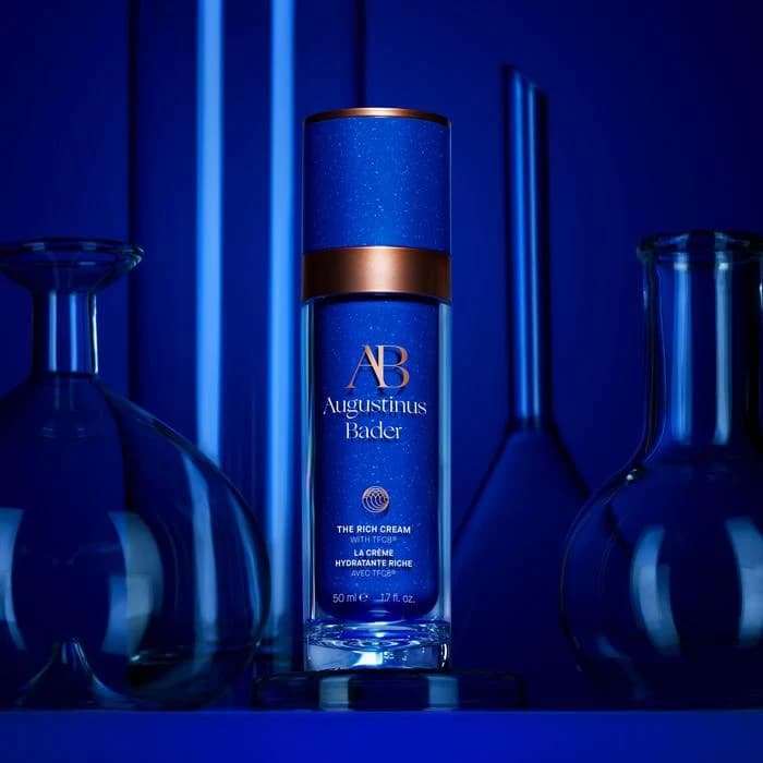 Augustinus Bader skin-care product in a blue studio composition